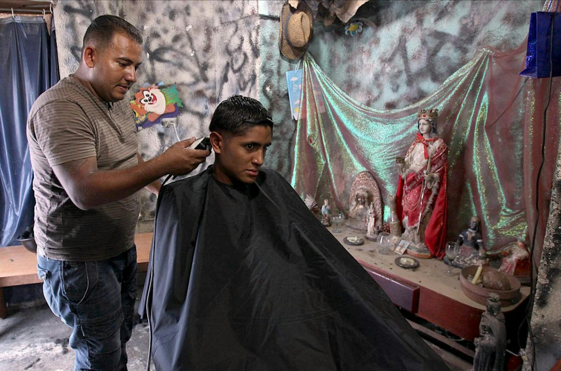 Barber/film director Jackson Gutierrez cuts the hair of a client in the Petare neighborhood of Caracas, Venezuela.