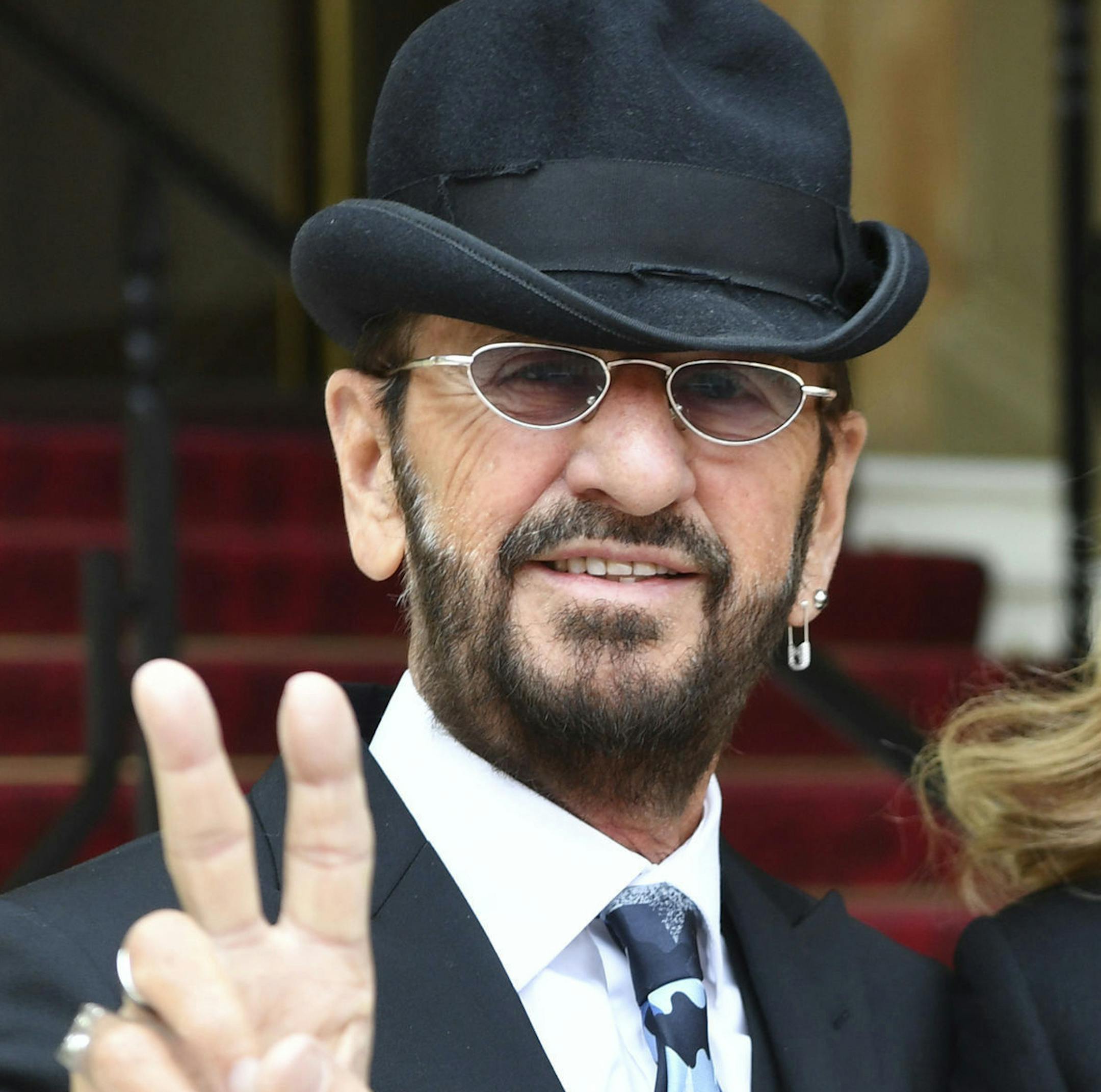 Musician Ringo Starr, left, gestures as he arrives with his wife Barbara Bach to receive his knighthood, at Buckingham Palace, in London, Tuesday March 20, 2018. (John Stillwell/PA via AP)