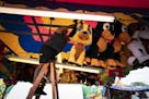Lorraine Robitaille, right, handed Margarita Nunez a large stuffed dog as they hung game prizes at their stand in the Midway on Wednesday, ahead of th