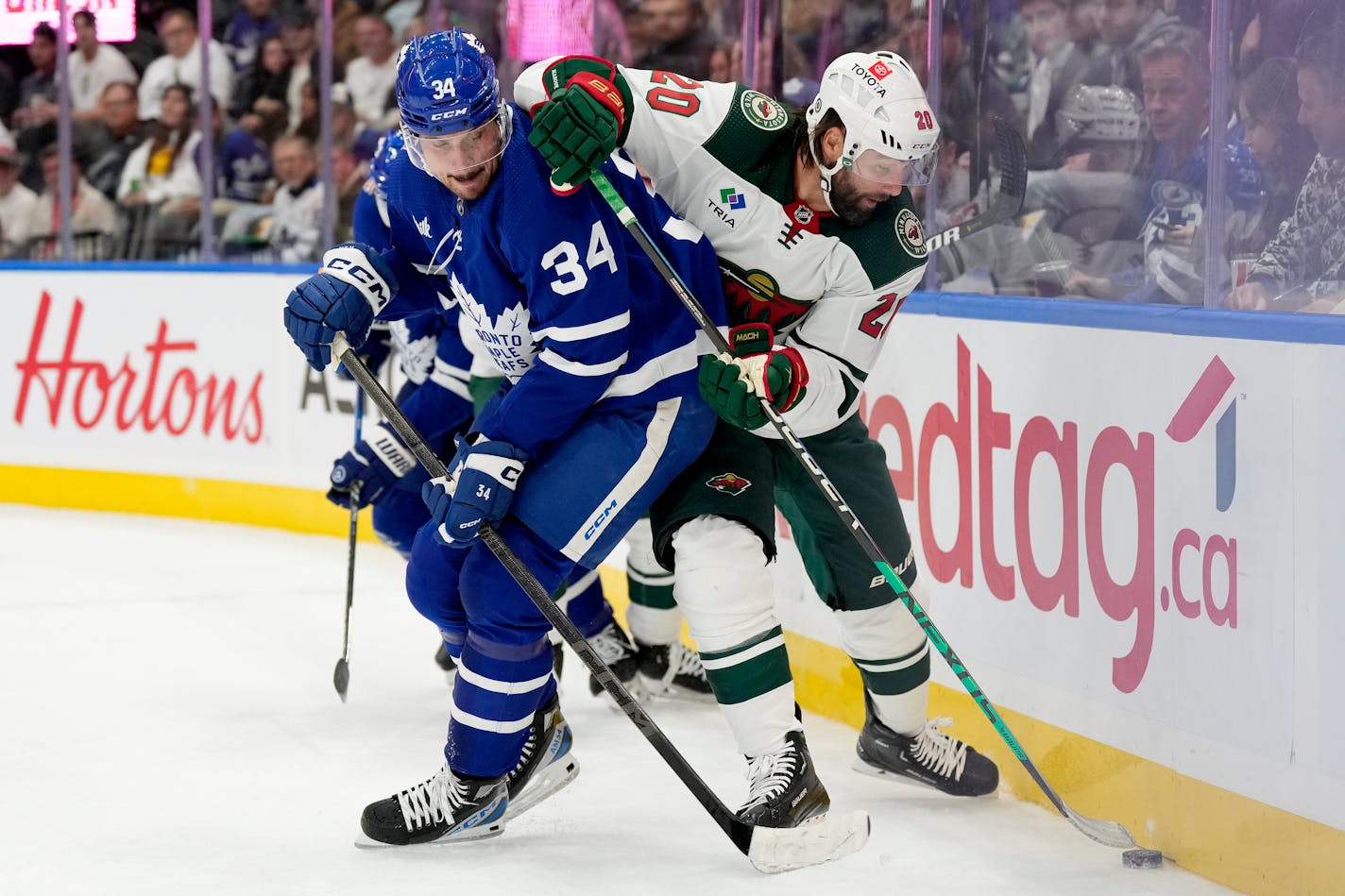 Toronto Maple Leafs center Auston Matthews (34) and Minnesota Wild left wing Pat Maroon (20) vie for control of the puck during the first period of an NHL hockey game in Toronto, Saturday, Oct. 14, 2023. (Frank Gunn/The Canadian Press via AP)