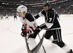 Los Angeles Kings defenseman Rob Scuderi, right, checks New Jersey Devils left wing Zach Parise during the first period of an NHL hockey game in Los A