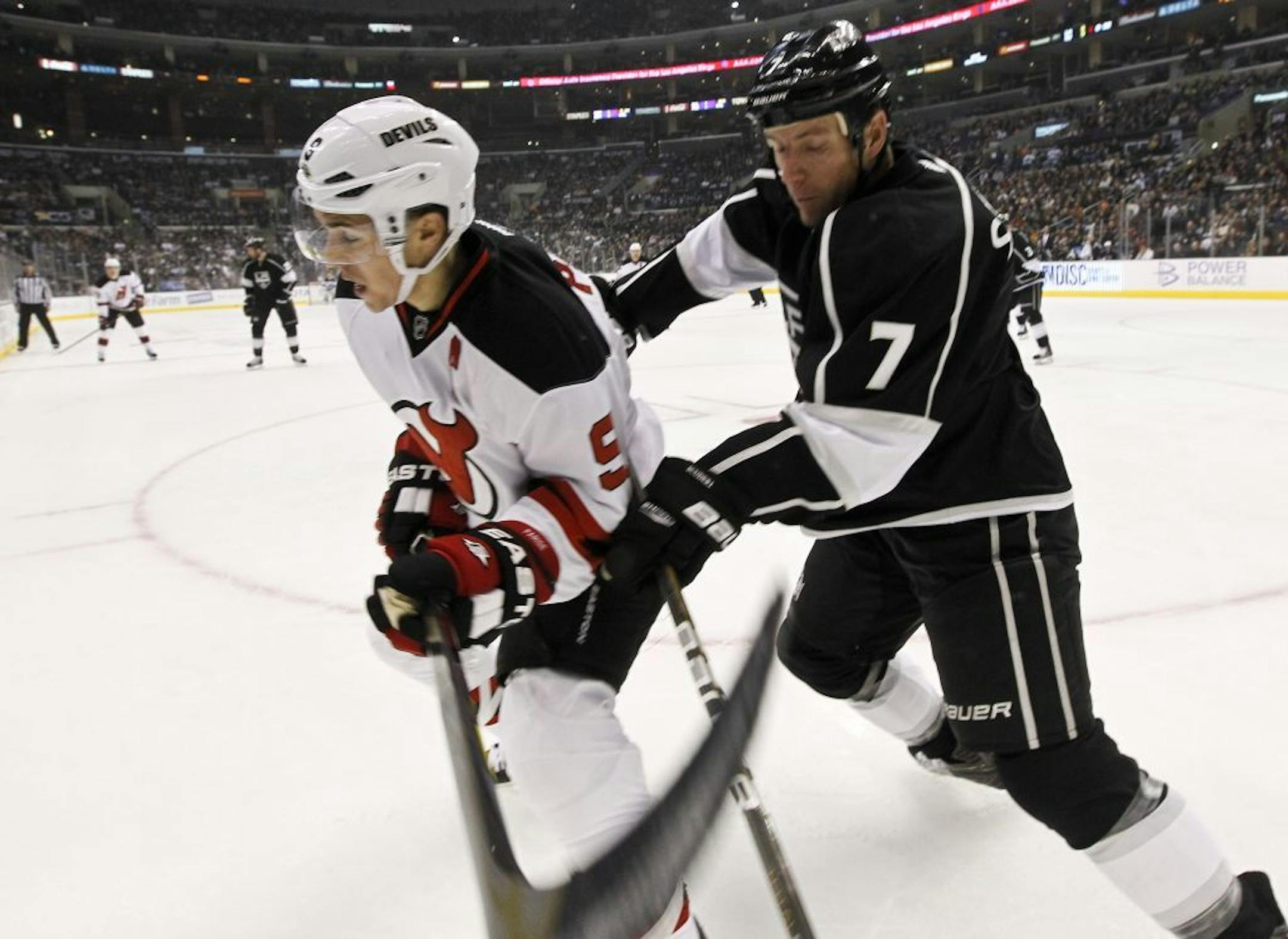 Los Angeles Kings defenseman Rob Scuderi, right, checks New Jersey Devils left wing Zach Parise during the first period of an NHL hockey game in Los Angeles, Tuesday, Oct. 25, 2011.