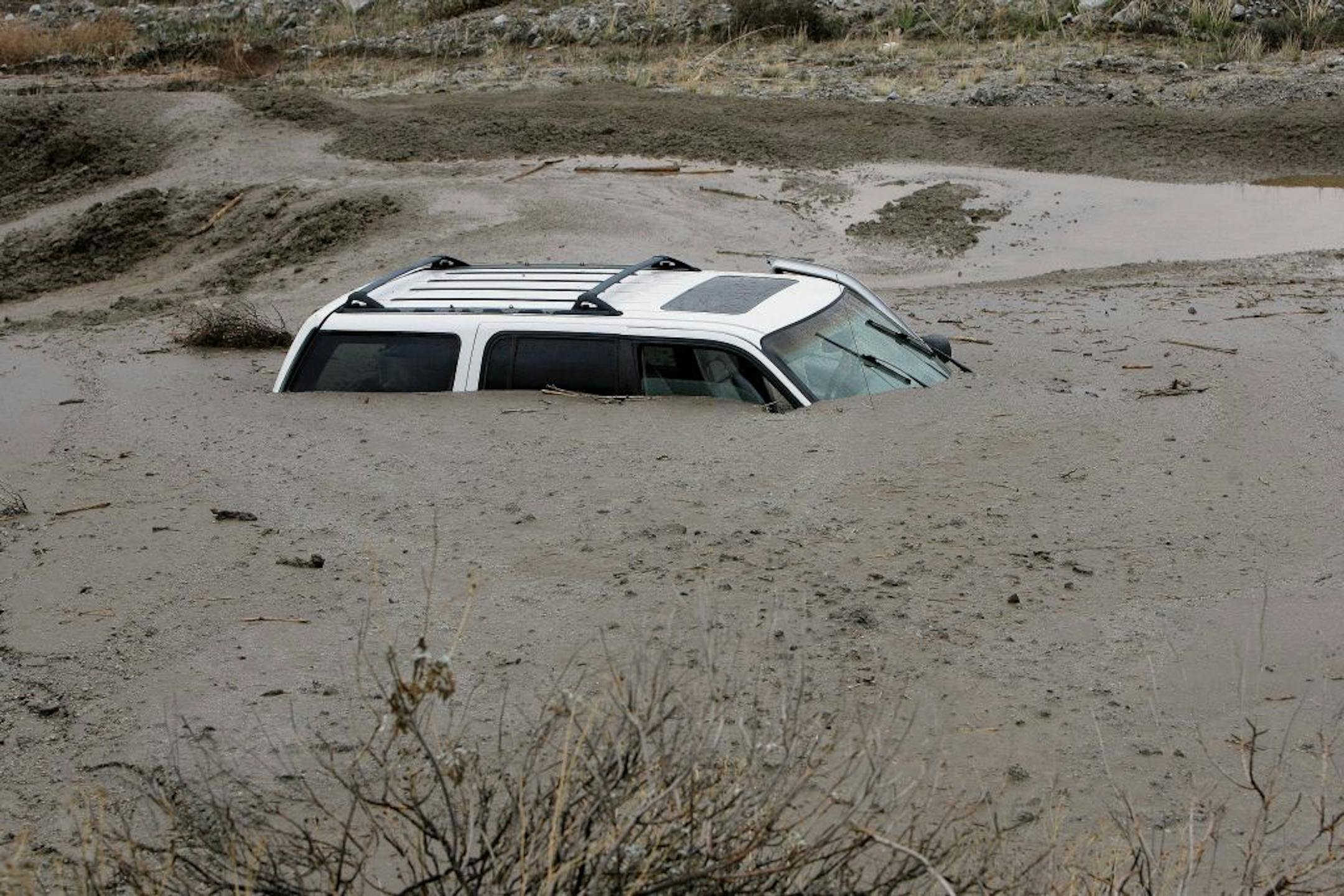 A vehicle sits in mud up to its windows on Soboba Road near Gilman Springs Road in San Jacinto, Calif. on Thursday, Dec. 4, 2014. Heavy rains triggered flash floods and stranded more than three dozen people in their cars in Southern California.