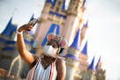 A guest stops to take a selfie at Magic Kingdom Park, July 11, 2020, at Walt Disney World Resort in Lake Buena Vista, Fla., on the first day of the th