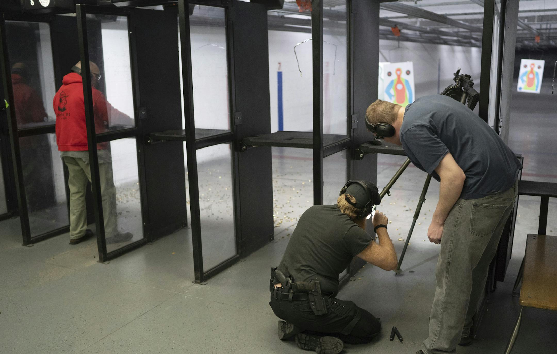 In this Dec. 1, 2018, photo, fifteen-year member Tony Piekarski loads a gun while member Eric Inman and ally Kevin Arndt fix a tripod inside of Bill's Gun Shop and Range in Circle Pines, Minn. The gun range provides safe space for LGBT gun rights group. (Evan Frost/Minnesota Public Radio via AP)