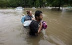 Margarita Uribe, left, and her husband, Juan Juarez, wade through floodwaters as they evacuate their flooded apartment complex Monday, April 18, 2016,