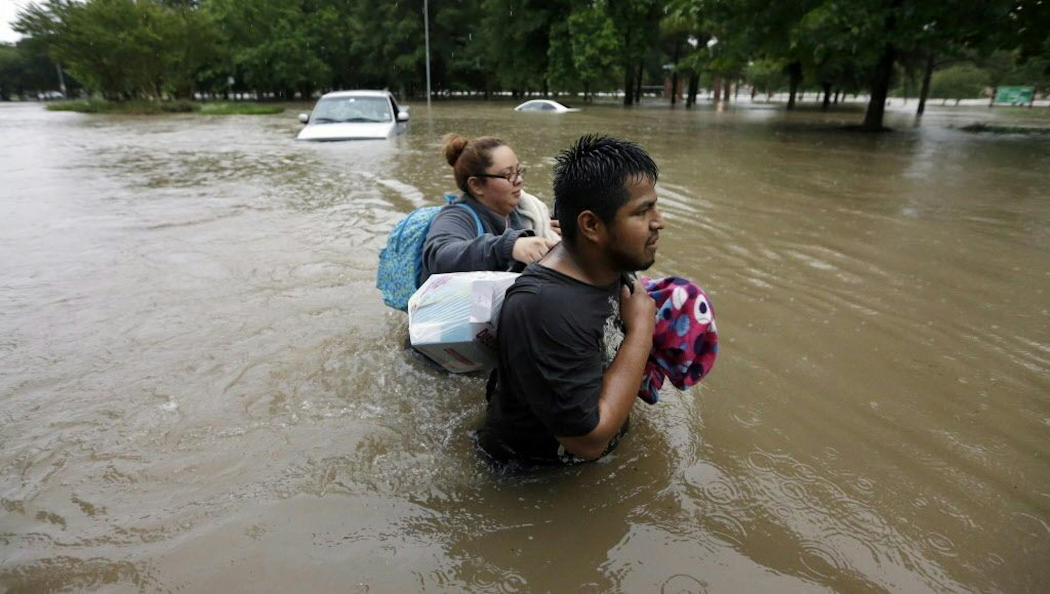Margarita Uribe, left, and her husband, Juan Juarez, wade through floodwaters as they evacuate their flooded apartment complex Monday, April 18, 2016, in Houston. Storms have dumped more than a foot of rain in the Houston area, flooding dozens of neighborhoods and forcing the closure of city offices and the suspension of public transit.