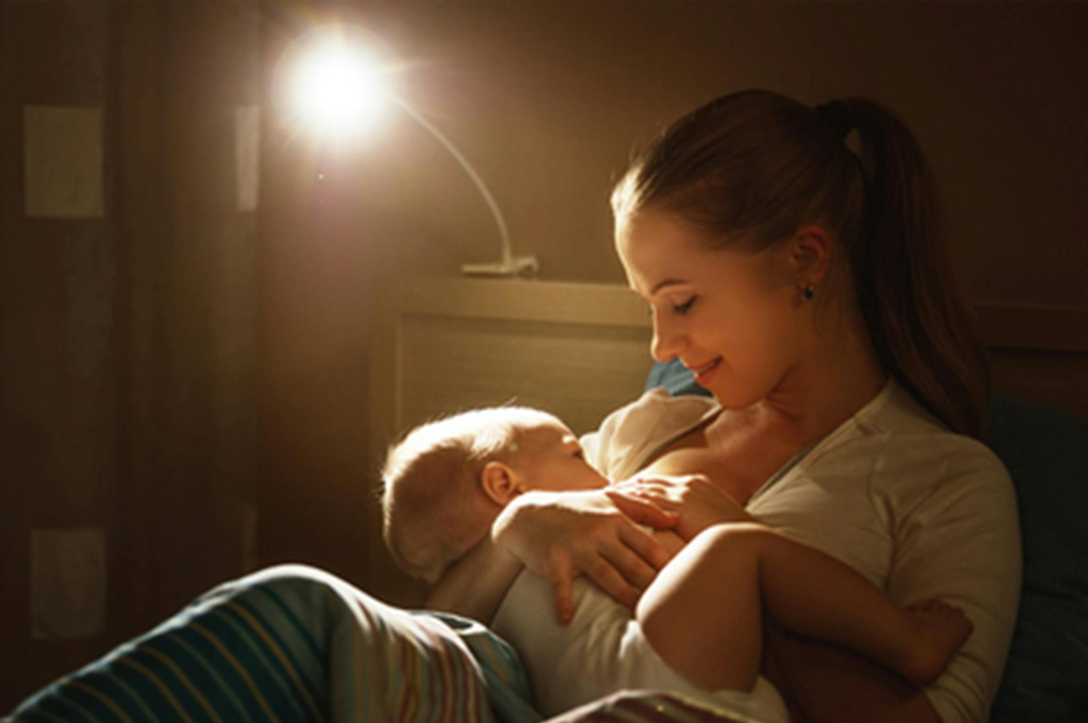 Breastfeeding. mother feeding baby breast in bed dark night(Dreamstime/TNS) ORG XMIT: 1233045