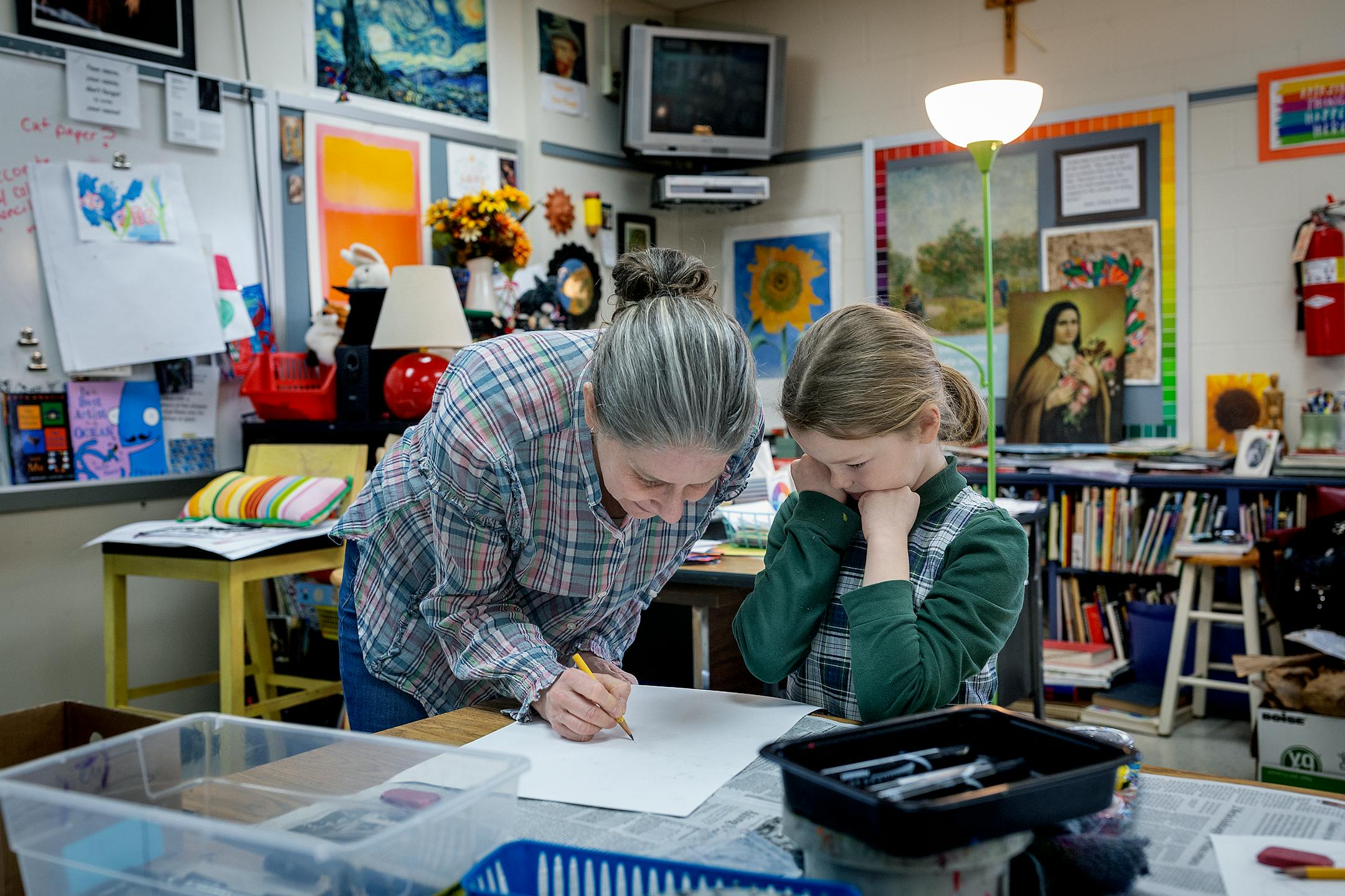 Teresa Peters works with Alex Arden during her third grade art class at St. Therese Catholic School.