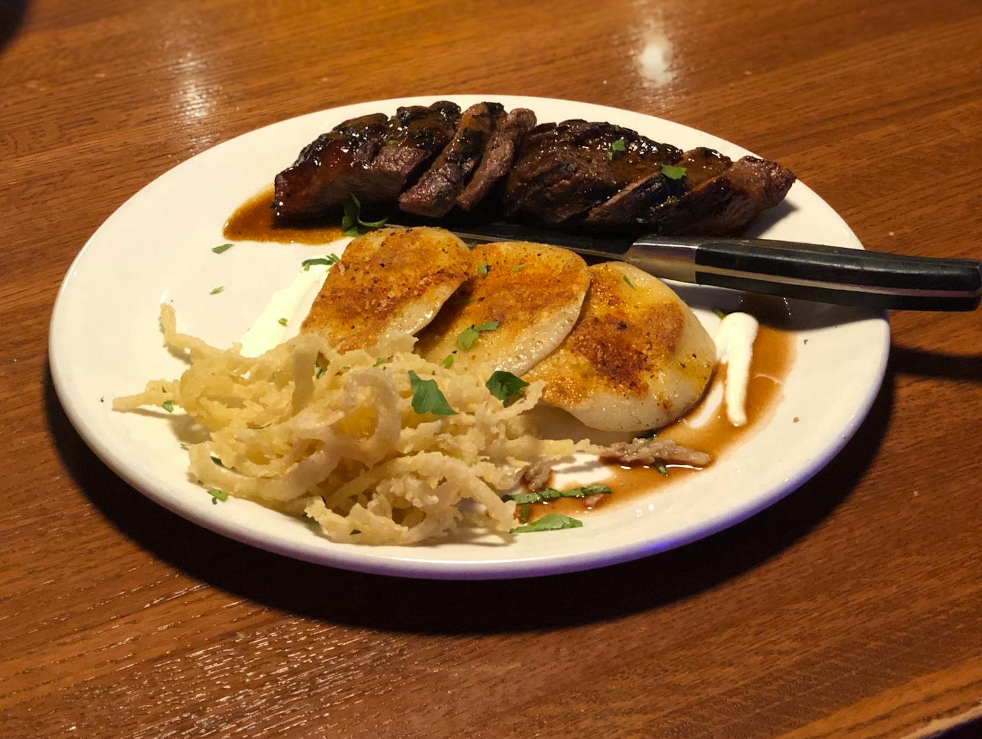 Sliced steak, cheese pierogies on top of a creamy horseradish sauce and tempura fried onions on a plate at 3 Squares restaurant in Maple Grove.