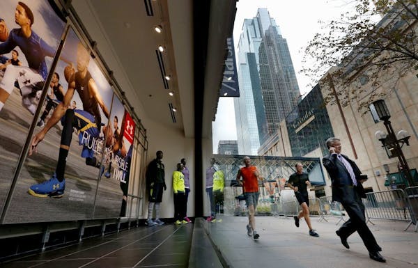 Pedestrians and runners passed a window display at the new Sports Authority downtown Minneapolis store on the Nicollet Mall.