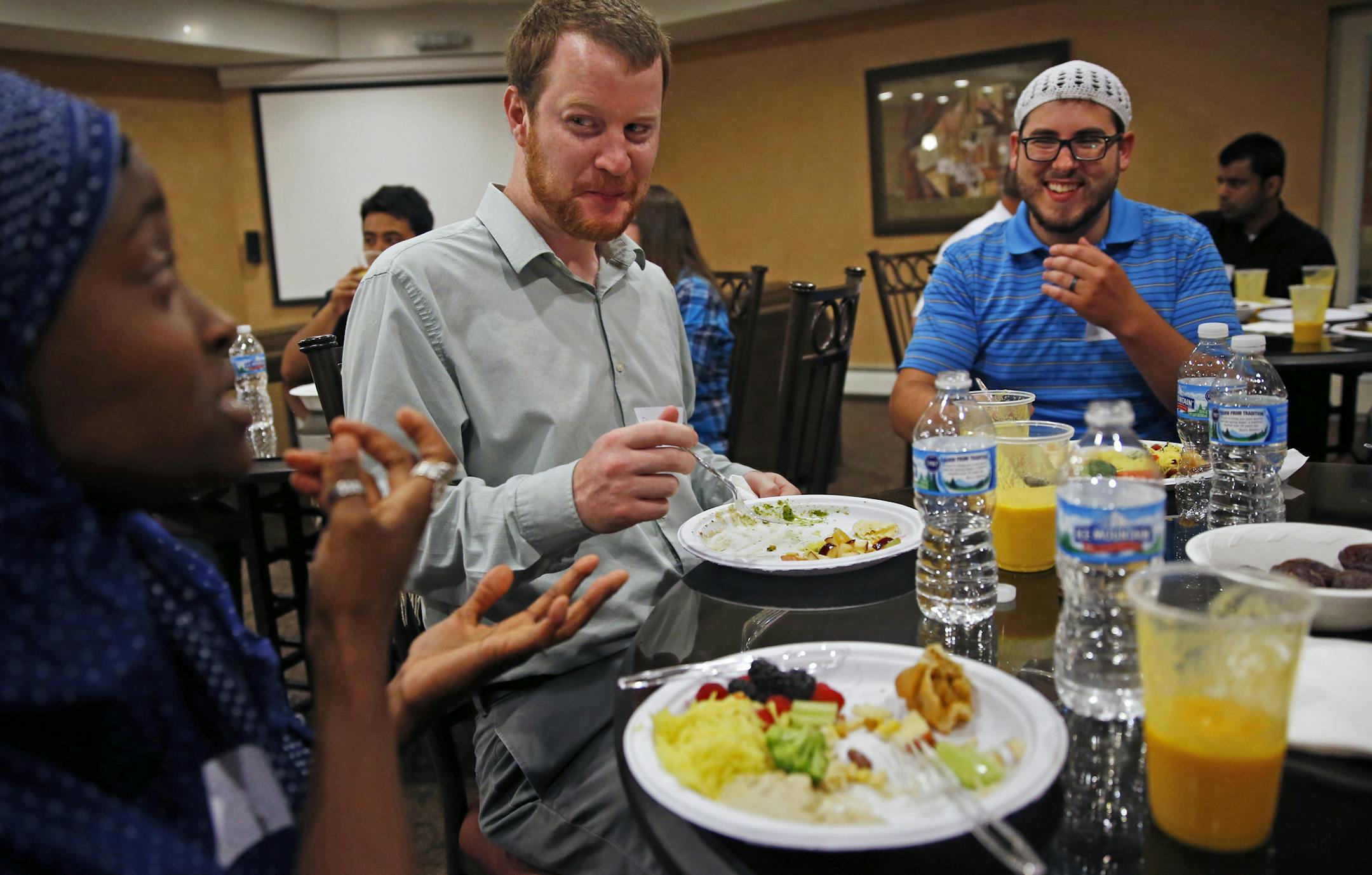 At the community room in an apartment complex in Woodbury, Mallerie Shirley, far left, and Chris Pleasants, far right, are a married couple who converted to Islam. Patrick Nervig, center, is a an non-Mulsim friend who was invited to participate in the iftar. Shirley was explaining some of the challenges of fasting and working during Ramadan.] tsong-taataarii@startribune.com