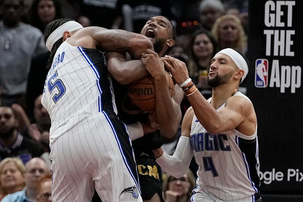 Cleveland Cavaliers forward Evan Mobley, center, fights for control of the ball with Orlando Magic forward Paolo Banchero (5) and guard Jalen Suggs (4