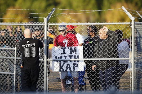 Fans watch from behind a fence as free agent quarterback Colin Kaepernick participates in a workout for NFL football scouts and media, Saturday, Nov. 