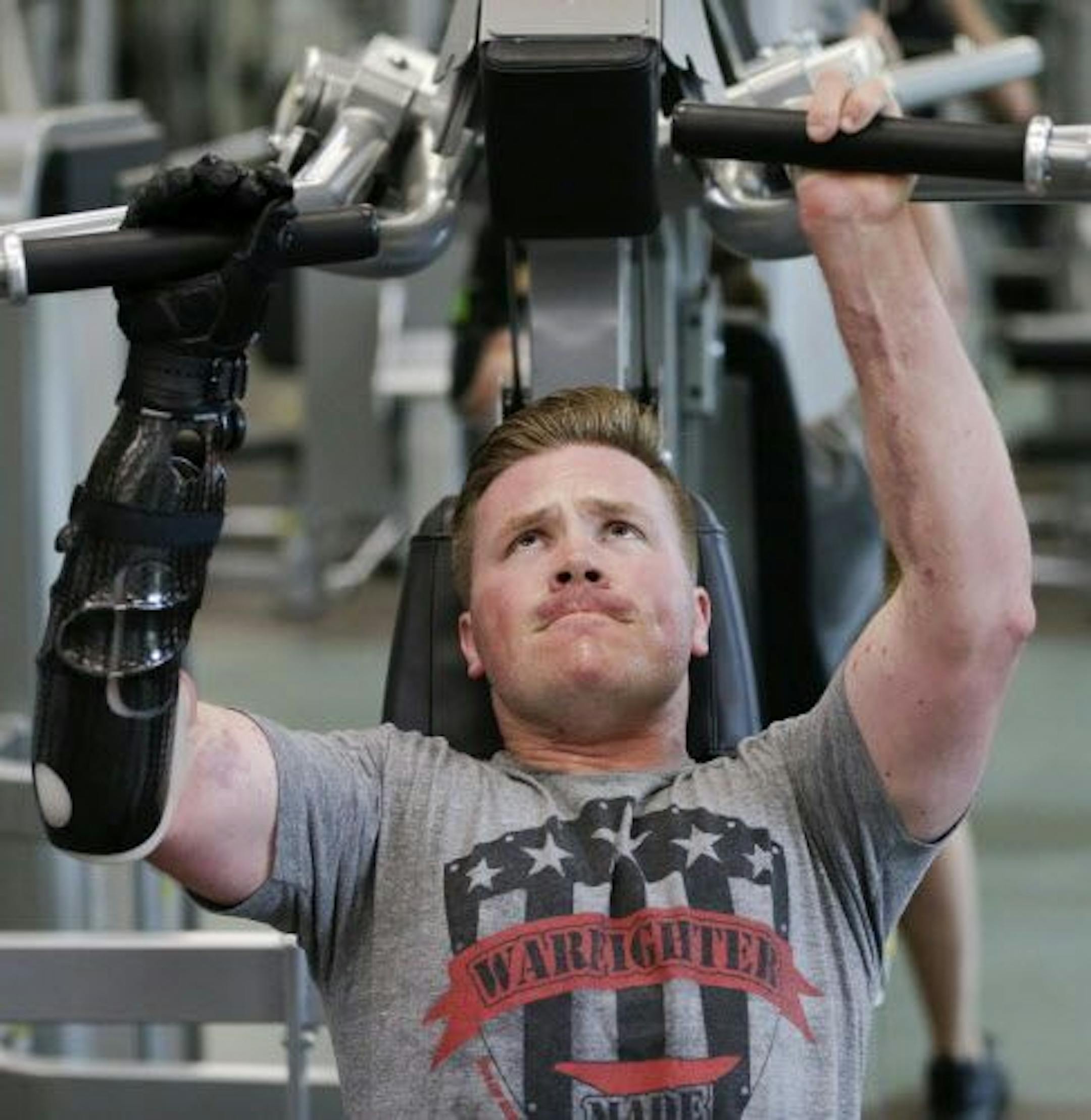 Retired Marine Gunnery Sgt. Brian Meyer grimaces as he grips a workout machine with a prosthetic arm and two fingers at the Wounded Warrior Hope & Care Center in Camp Pendleton, Calif.