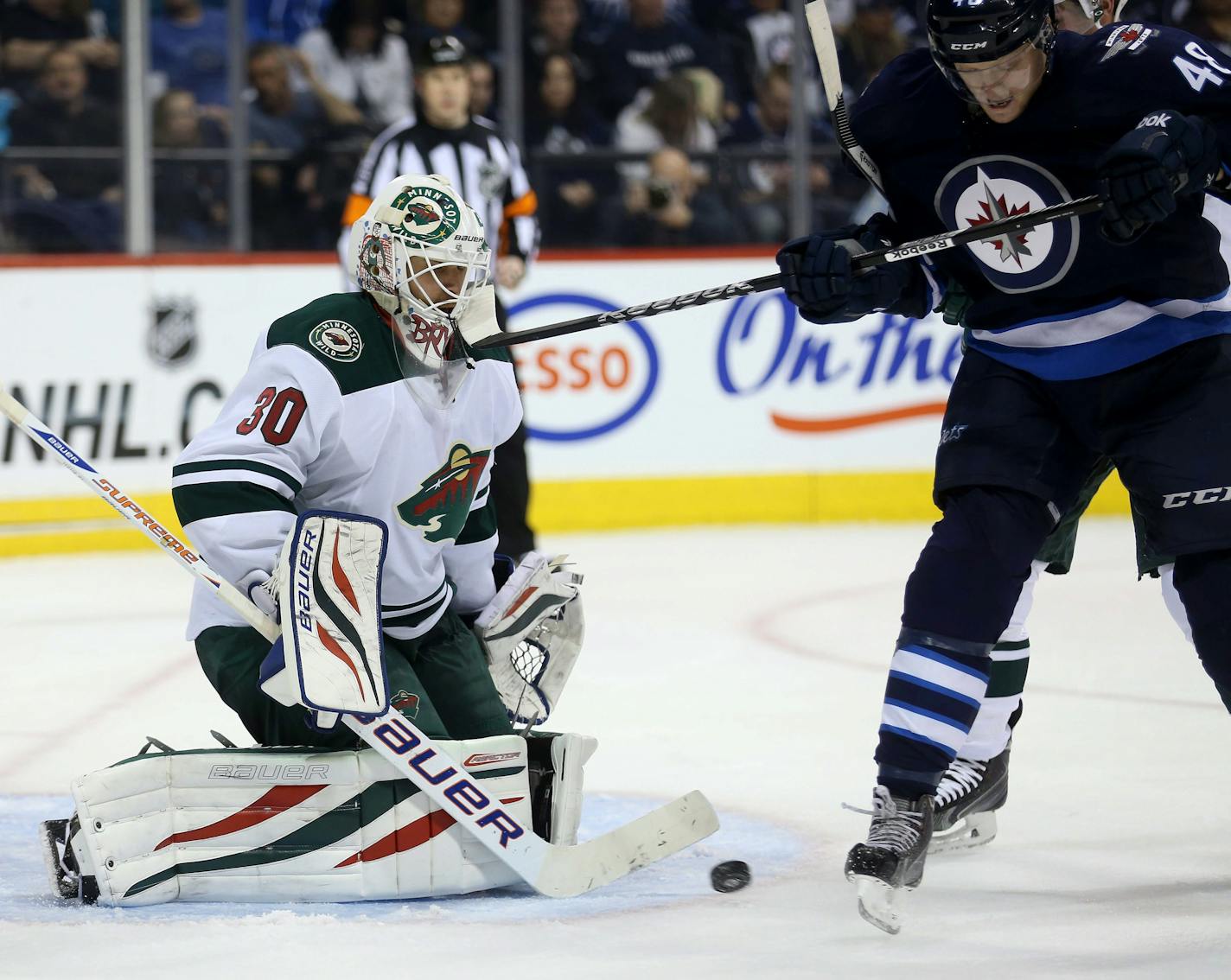 Minnesota Wild's Ilya Bryzgalov (30) takes a stick to the mask by Winnipeg Jets' Carl Klingberg (48) during second period NHL hockey action in Winnipeg, Manitoba, Monday, April 7, 2014. (AP Photo/The Canadian Press, Trevor Hagan)