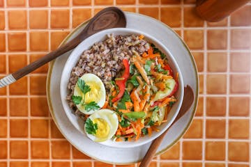 A grain bowl with grains of wild rice and Kernza topped with vegetables and a hard-cooked egg.