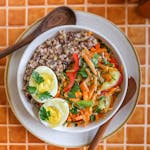 A grain bowl with grains of wild rice and Kernza topped with vegetables and a hard-cooked egg.