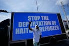 A man chants in front of a billboard truck reading “Stop the Deportation of Haitian Refugees,” as members of Miami’s Haitian community protest a