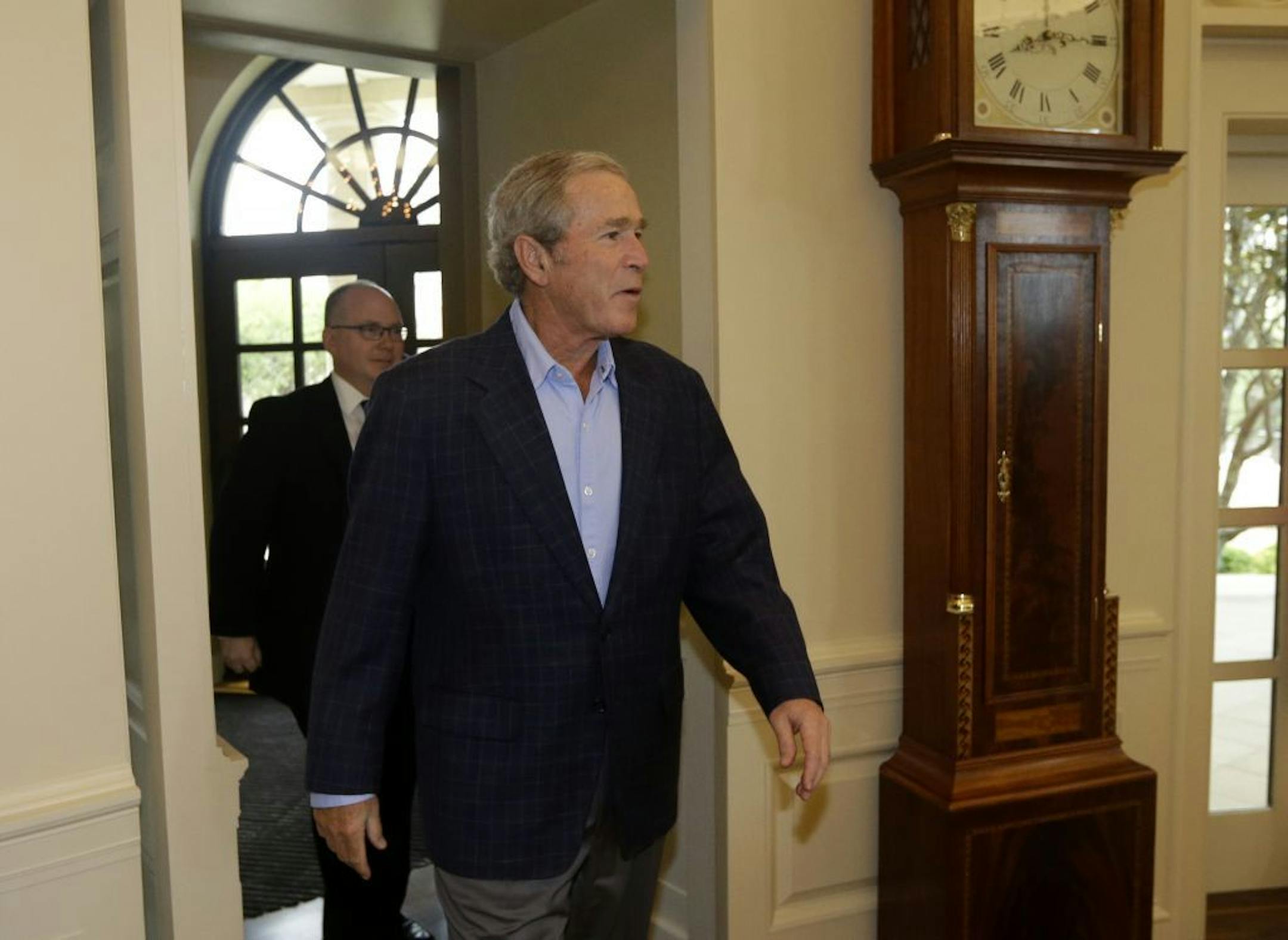 Former President George W. Bush walks into the oval office replica at the Bush Presidential Library as he surprises 43 Dallas-Fort Worth school children who were the first official guest of the museum on its' opening day Wednesday, May 1, 2013, in Dallas.