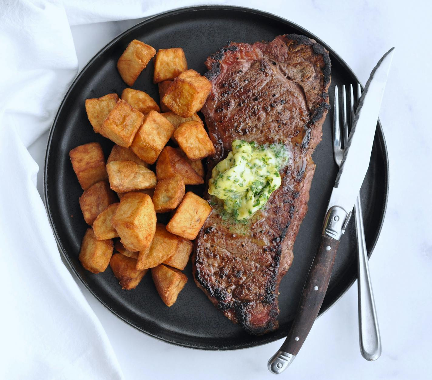 Enjoy a homemade version of Steak Frites with this steak, potatoes, and herb-filled butter.