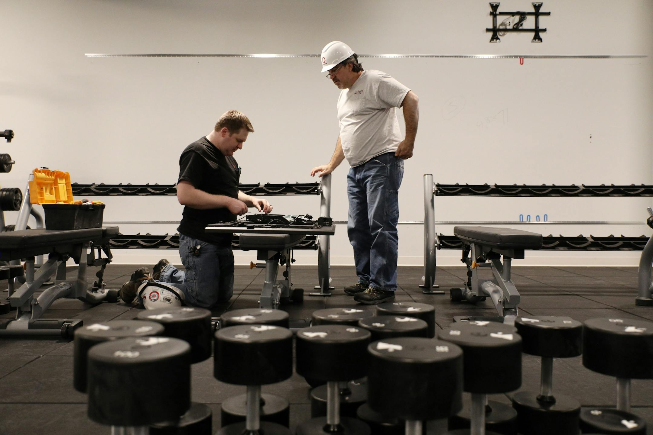 Justin Boie, left, and Vladimir Bazelkov with Parsons Technologies worked to install television screens in the weight room area.