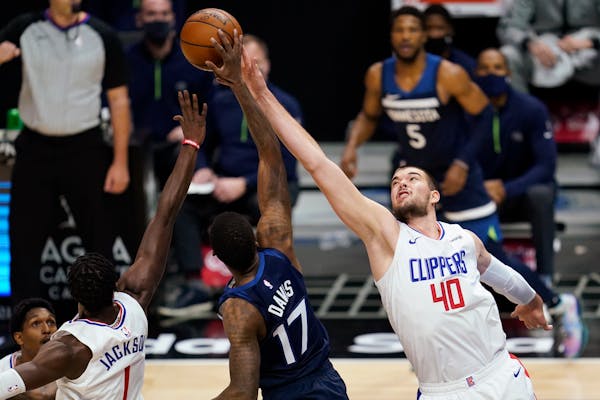 Los Angeles Clippers guard Reggie Jackson, left, and center Ivica Zubac and Timberwolves forward Ed Davis reach for a rebound during the first quarter