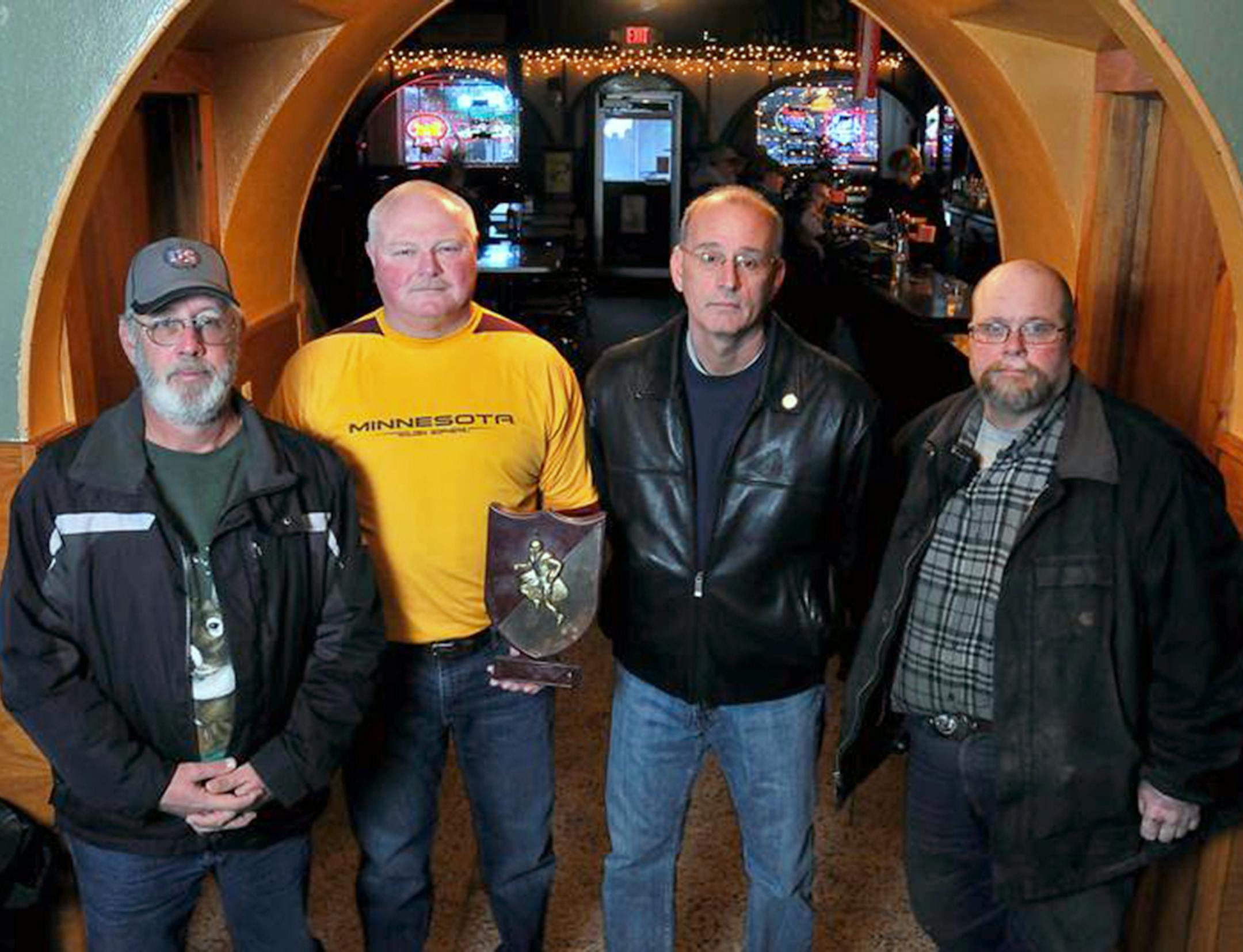 Eveleth High School 1973 state championship teammates from left, Jeff Perushek, Greg Salmi, Bob Pazzelli, and John Rauzi pose with a commemorative plaque from their season at Margie's Roosevelt Bar in Eveleth.