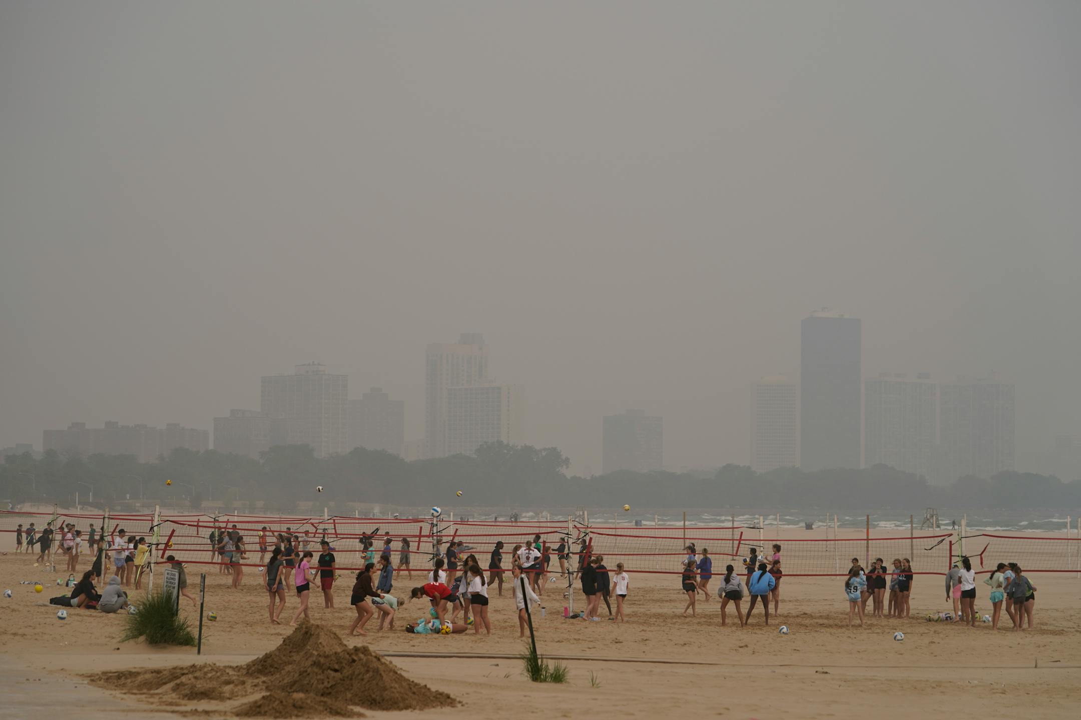 Children participate in a summer camp on Montrose Beach as buildings behind the shore are blanketed in haze from Canadian wildfires in Chicago.