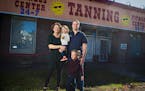 Sarah and Seth Maxim pose with their children in front of the former gym and tanning salon in Duluth's Lakeside neighborhood where they plan to move L