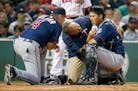 Minnesota Twins manager Paul Molitor (4) and a trainer tend to Kurt Suzuki, right, who was injured on a pitch during the second inning of a baseball g
