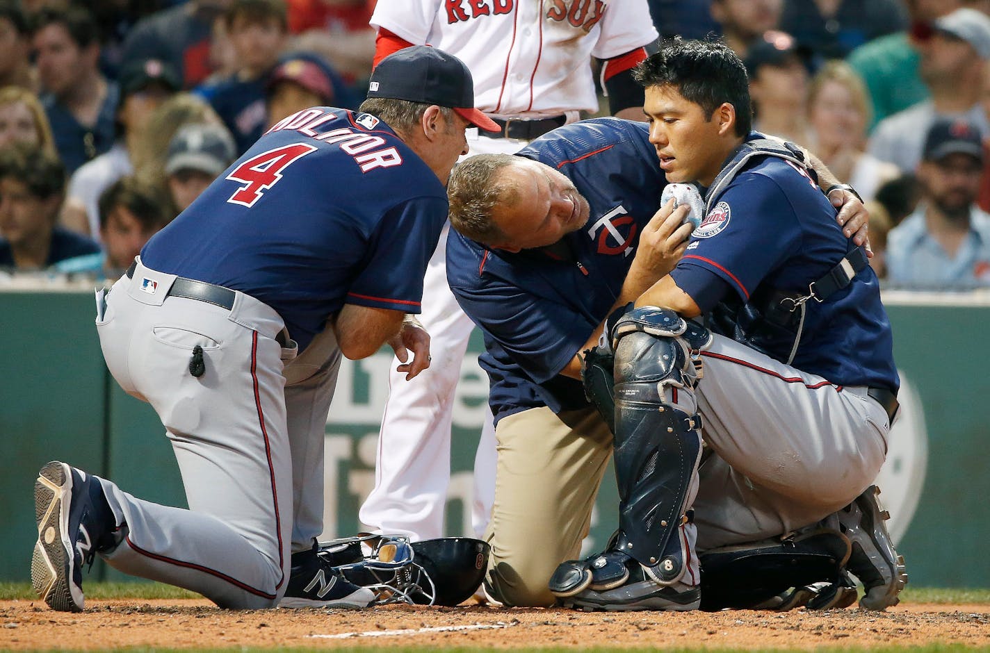 Minnesota Twins manager Paul Molitor (4) and a trainer tend to Kurt Suzuki, right, who was injured on a pitch during the second inning of a baseball game against the Boston Red Sox in Boston, Saturday, July 23, 2016. Suzuki left the game. (AP Photo/Michael Dwyer)