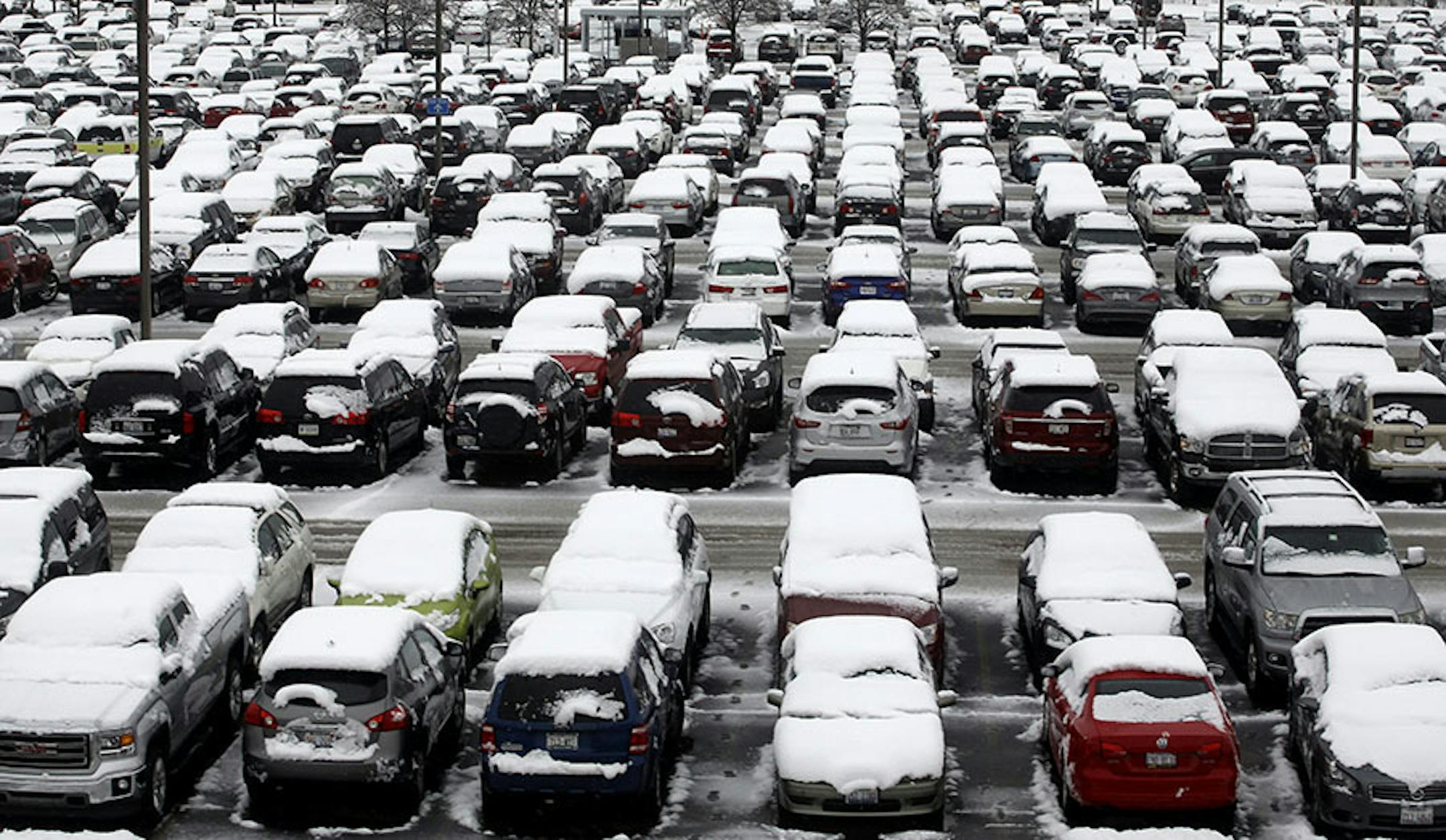 Cars are covered by snow in general parking lot at O'Hare International Airport, Saturday, Nov. 21, 2015, in Chicago. The first significant snowstorm of the season blanketed some parts of the Midwest with more than a foot of snow and more was on the way Saturday, creating hazardous travel conditions and flight delays.