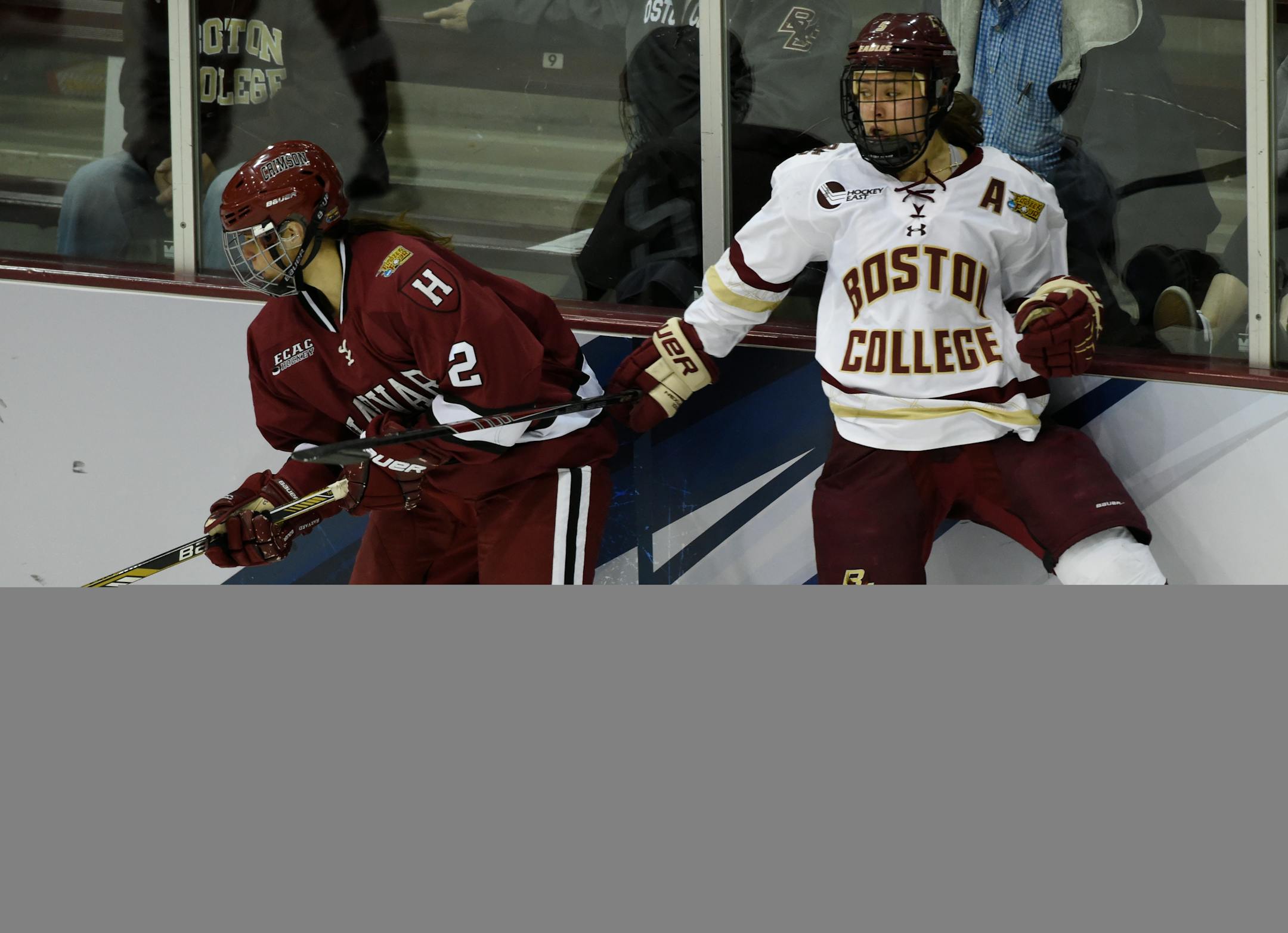 Harvard defender Josephine Pucci (2) and Boston College forward Alex Carpenter (5) collide with the boards during the third period of an NCAA women's Frozen Four semifinal college hockey game Friday, March 20, 2015, in Minneapolis. Harvard won 2-1. (AP Photo/Hannah Foslien)