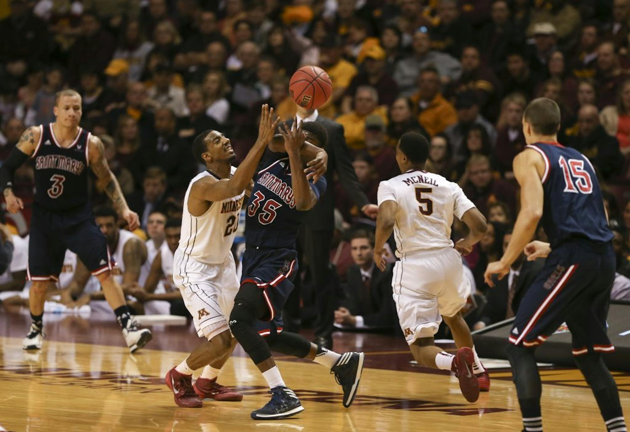 Gophers guard Austin Hollins (20) tried to strip the ball from St. Mary's Gaels guard James Walker III (35) at midcourt in the first half.