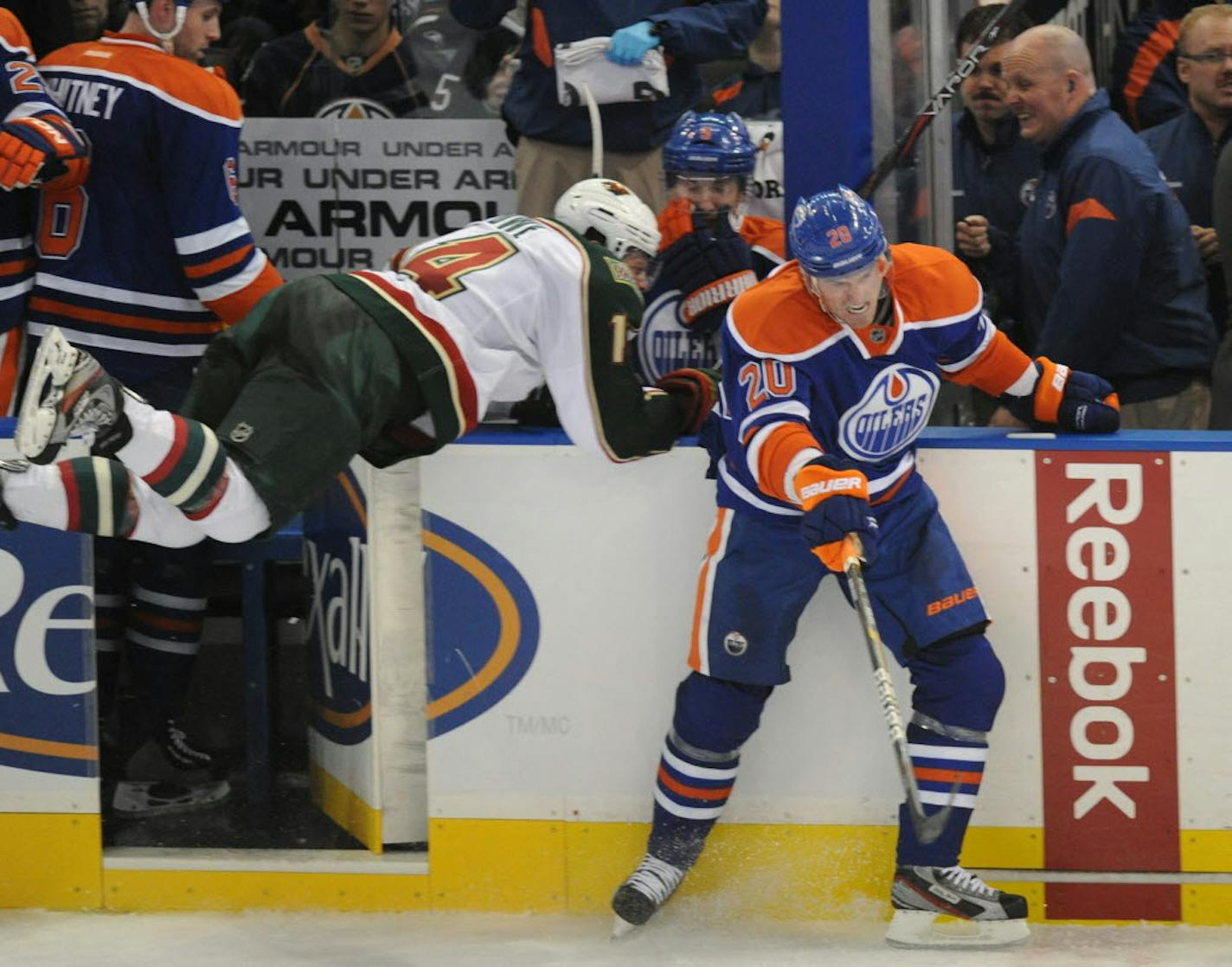 Edmonton's Eric Belanger, right, slips out of the way as Minnesota's Darroll Powe slams into the open door of the Oilers' bench.