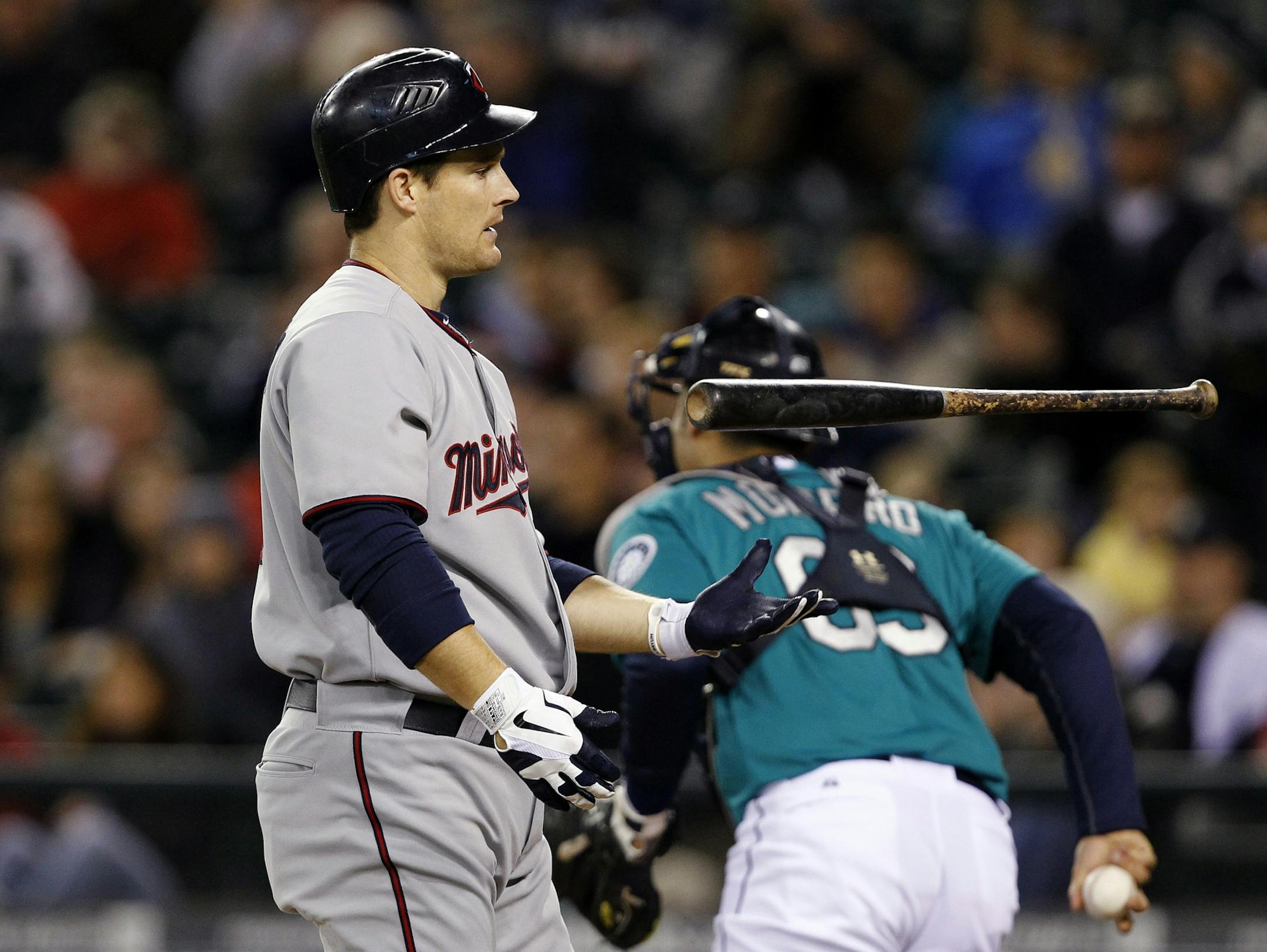 Minnesota Twins' Josh Willingham, left, flips his bat after striking out as Seattle Mariners catcher Jesus Montero heads to the dugout in the first inning of a baseball game, Friday, May 4, 2012, in Seattle.