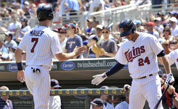 Trevor Plouffe, right, welcomed Joe Mauer back to the dugout after Mauer scored on a double by Ryan Doumit in the fourth inning of the Twins' 11-3 vic