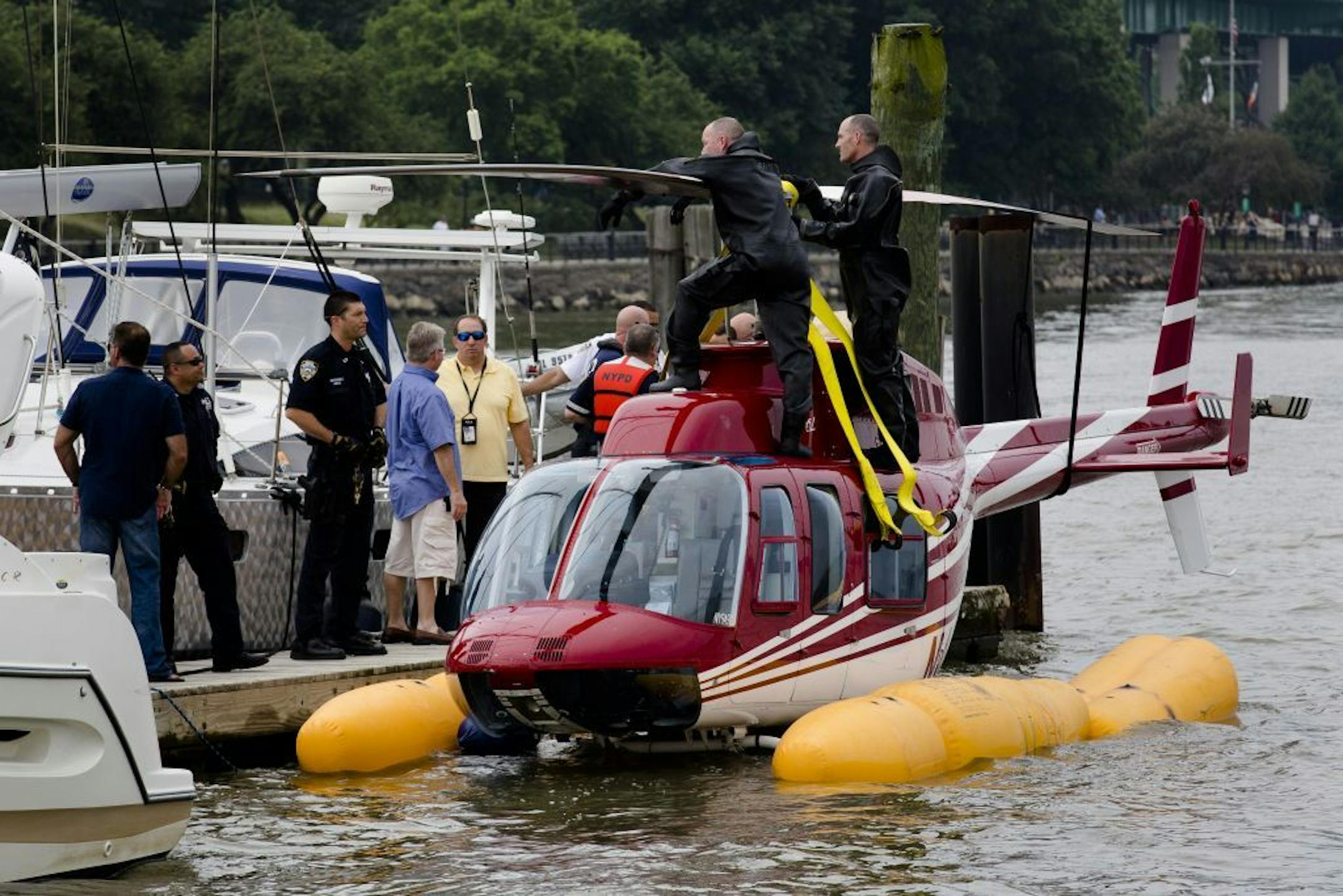 A helicopter rests on a pontoon at the 79th Street Boat Basin after an emergency landing over the Hudson river, Sunday, June 30, 2013, in New York. New York authorities say a helicopter carrying four Swedish tourists landed in the Hudson River off Manhattan Sunday, but everyone has been rescued.