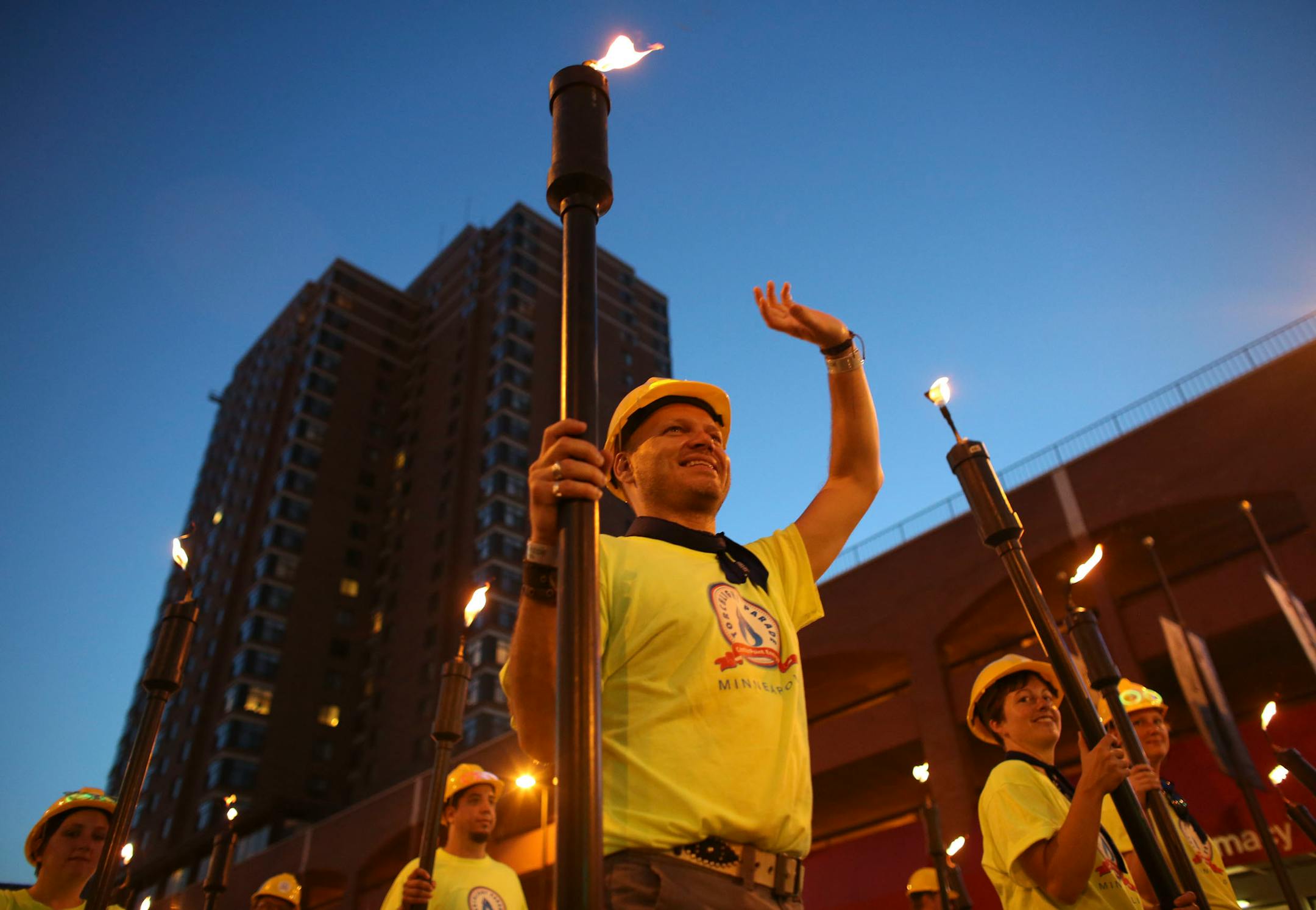 In this file photo, CenterPoint volunteers carried torches and waved during Torchlight Parade along Hennepin Ave in Minneapolis Min., Wednesday, July 17, 2013.