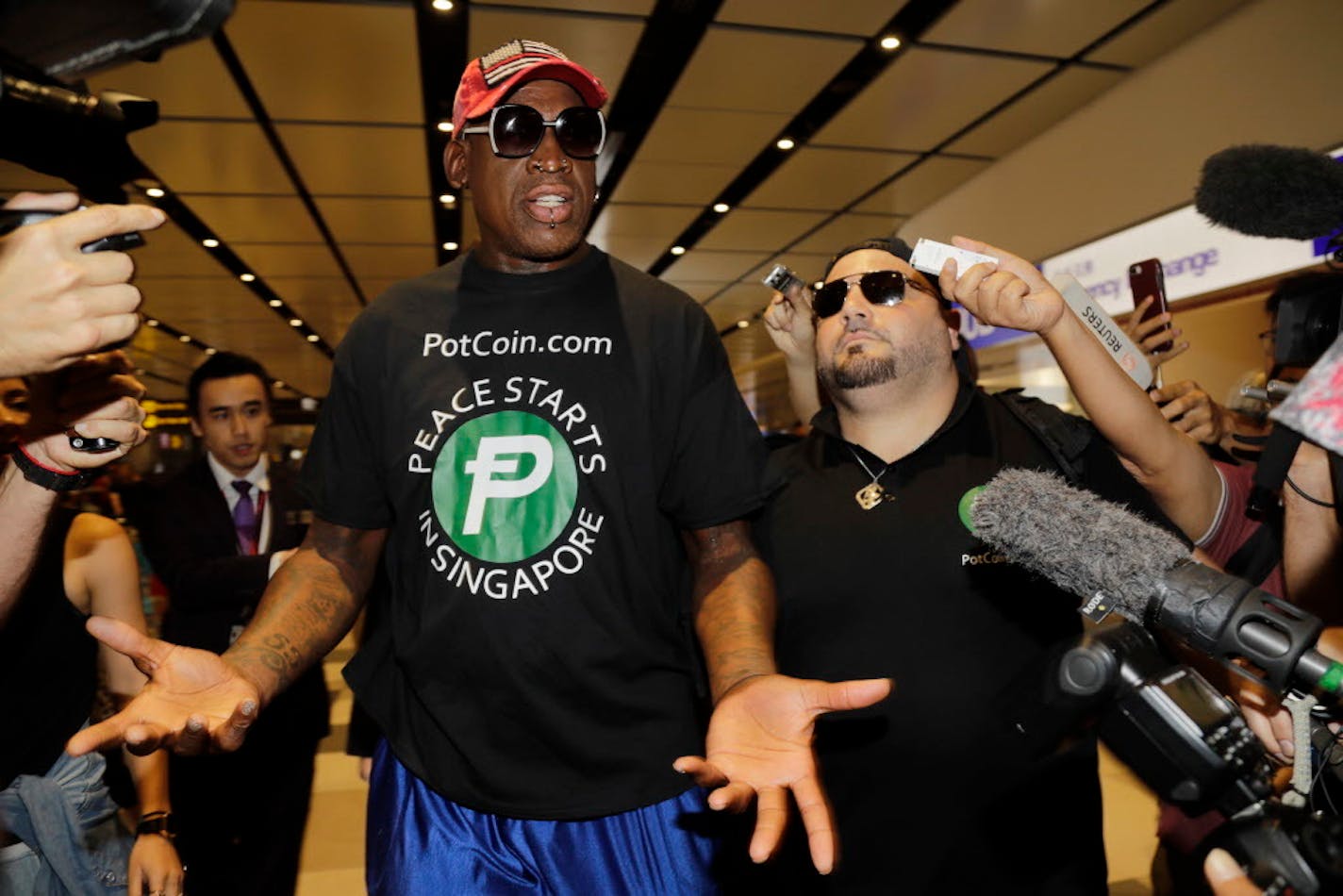 Former NBA basketball player Dennis Rodman, and Chris Volo, right, arrive at Singapore's Changi Airport on Tuesday, June 12, 2018.