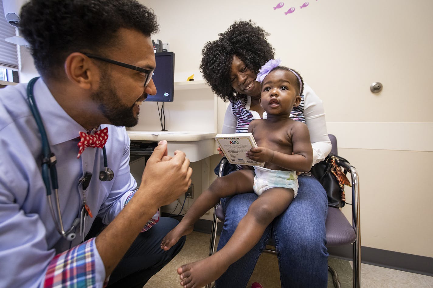 Dr. Nathan Chomilo gives 15-month-old Tedra Gbelia a book at the beginning of her well-child visit with her mother Lorpu Cyrus. ] LEILA NAVIDI &#xef; leila.navidi@startribune.com BACKGROUND INFORMATION: Dr. Nathan Chomilo sees 15-month-old Tedra Gbelia for a well-child visit with her mother Lorpu Cyrus at Park Nicollet Clinic in Brooklyn Center on Friday, July 13, 2018.