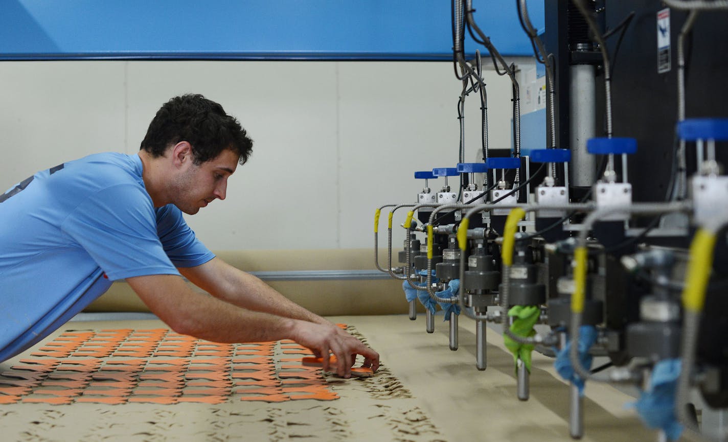 YOXO employee Thomas Miernicki, of St. Paul, picked up wood pieces after operating the high pressure water jet machine that uses 66 thousand pounds of water pressure as part of the YOXO toy packages at the YOXO production building in St. Paul, Minn., on Wednesday June 3, 2015. YOXO toys are built from eco-friendly materials, primarily recycled wood pulp. The toys include construction kits with suggested creations but can connect with all different kinds of objects. ] RACHEL WOOLF rachel.woolf@st