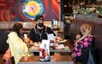 Server Luis Gonzalez brings friends Jasheena Bond and Erica Mooring their food order at the Smack Shack on Friday, Jan. 21, 2022 in Minneapolis, Minn.