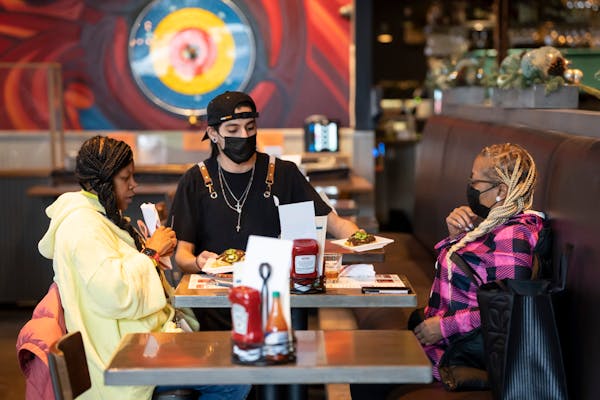 Server Luis Gonzalez brings friends Jasheena Bond and Erica Mooring their food order at the Smack Shack on Friday, Jan. 21, 2022 in Minneapolis, Minn.