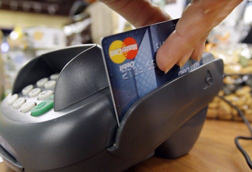 A customer swipes a MasterCard debit card through a machine while checking-out at a shop in Seattle.