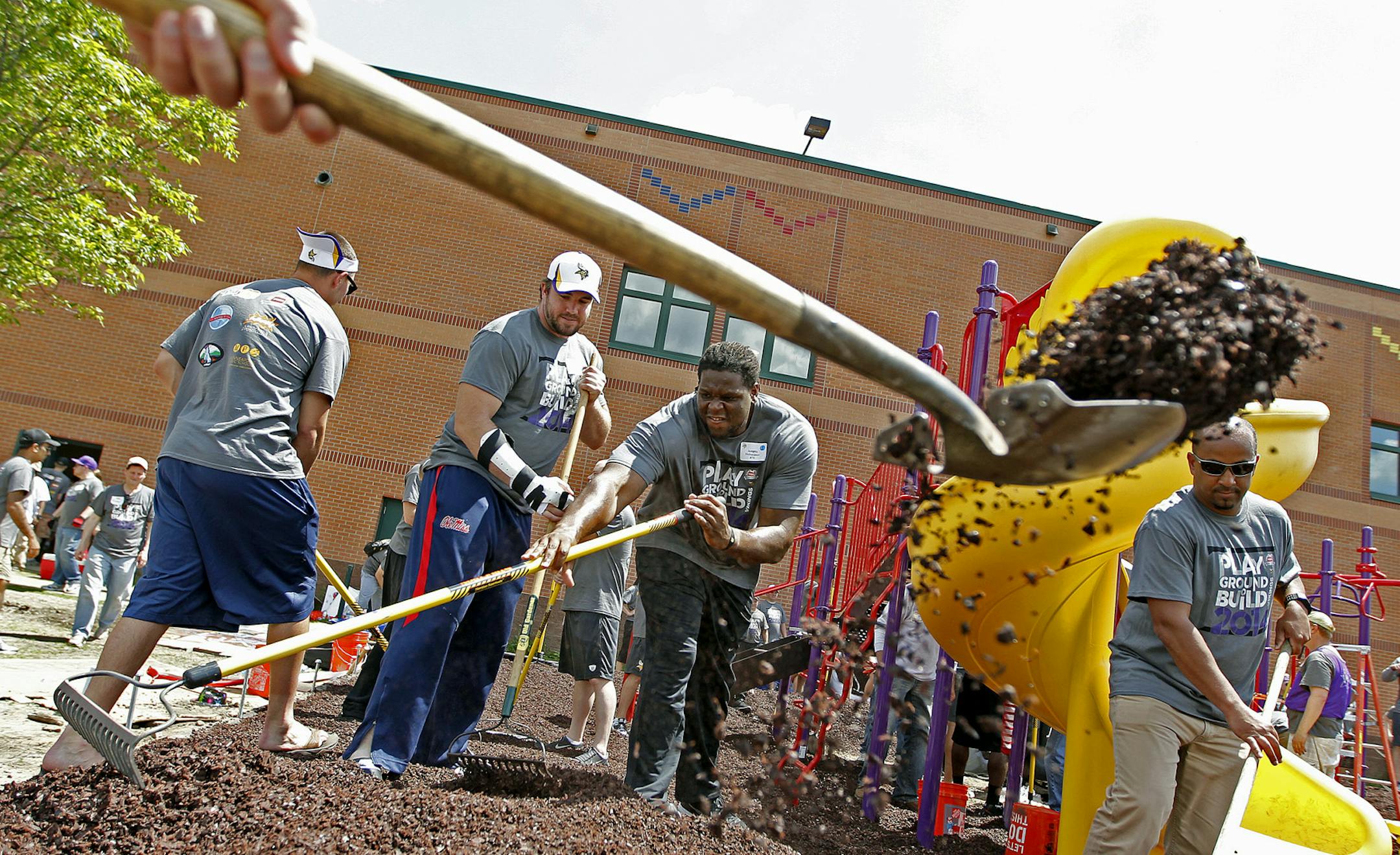 Minnesota Vikings Pierce Burton, left, and Antonio Richardson, center, joined other players, coaches, and school staff to help build a playground at Lucy Craft Laney School during the annual Vikings Playground Build, Wednesday, June 4, 2014 in Minneapolis, MN. ] (ELIZABETH FLORES/STAR TRIBUNE) ELIZABETH FLORES • eflores@startribune.com