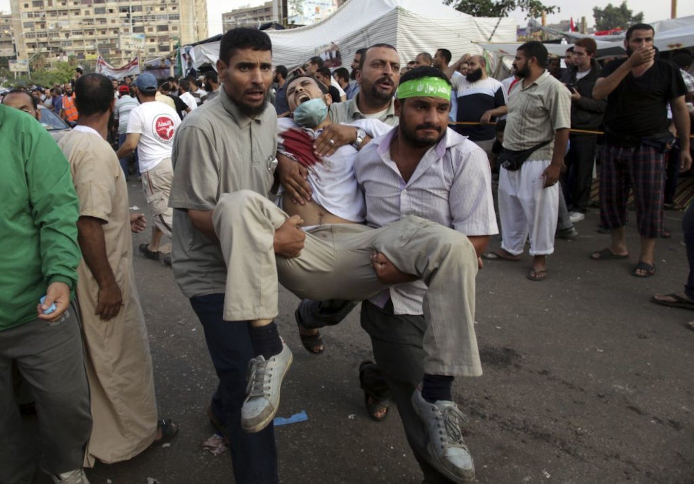 Supporters of Egypt's ousted President Mohammed Morsi carry an injured man to a field hospital following clashes with security forces at Nasr City, where pro-Morsi protesters have held a weeks-long sit-in, in Cairo, Egypt, Saturday, July 27, 2013. Overnight clashes between security forces and supporters of ousted Egyptian President Mohammed Morsi in east Cairo left dozens of protesters dead following a day of massive pro-military rallies backing a tough hand against Morsi�s backers and the Musli