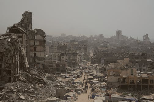 People walk along a street lined with destroyed buildings following Israeli bombardments during the Israel-Hamas war in the Gaza Strip on July 29.