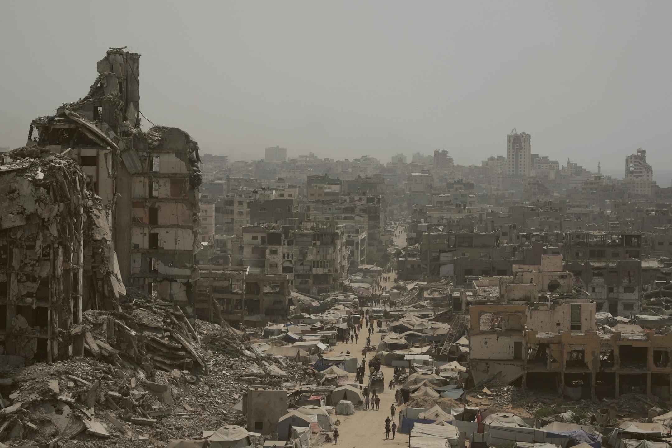People walk along a street lined with destroyed buildings following Israeli bombardments during the Israel-Hamas war in the Gaza Strip on July 29.